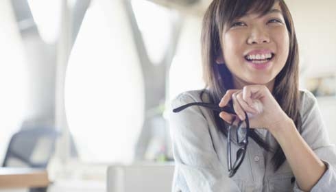 一位女性商務人士在辦公室里拿著眼鏡微笑