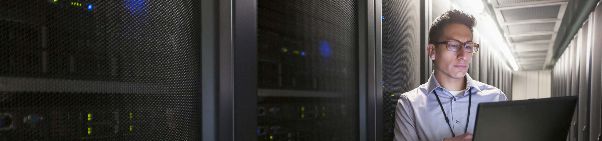 Confident server room technician at laptop.